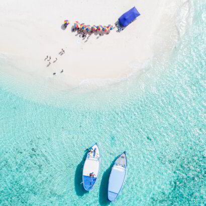Small boats beached on a white sandbank in a shallow lagoon