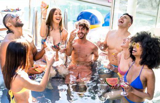 Group of friends laughing together in a pool on a sunny day