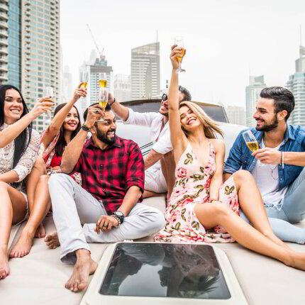 Friends raising a toast on the deck of a yacht with city towers behind