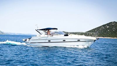 White motor yacht cruising along a green coastline