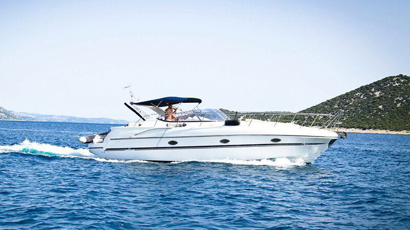 White motor yacht cruising past a green coastline