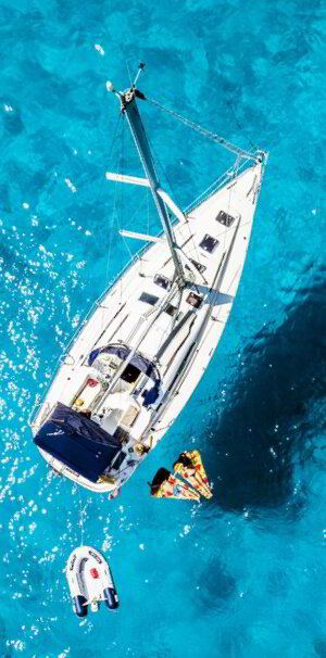 Sailboat at anchor seen from above with a small tender alongside