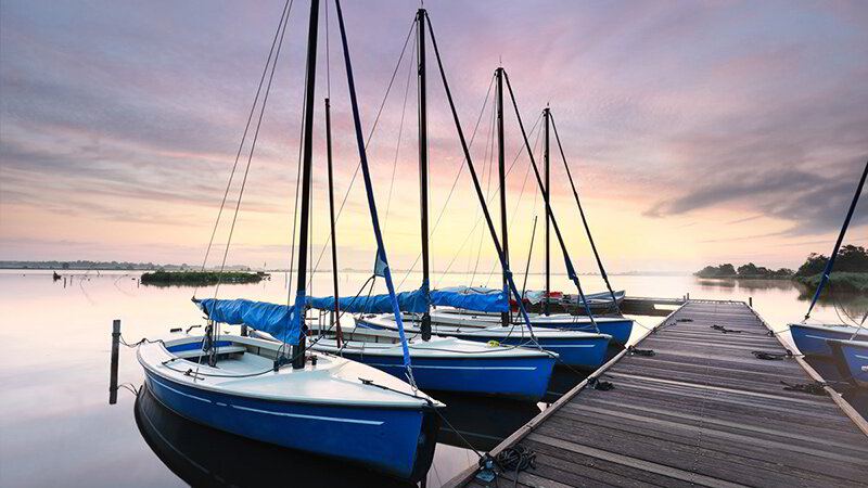 Sailboats tied to a wooden pier at sunset