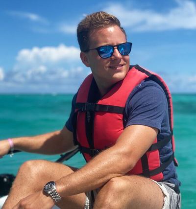 Boater wearing a red life vest at the helm of a small boat