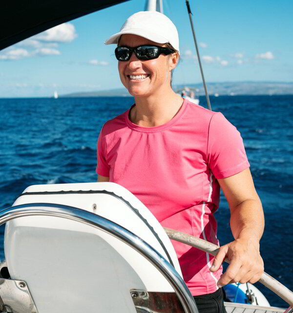 Smiling skipper in sunglasses at the wheel of a sailboat
