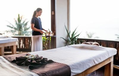 Spa therapist preparing a massage table on a sunny terrace