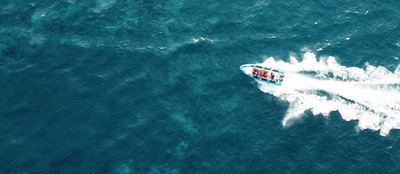 Speedboat leaving a white wake across open blue water