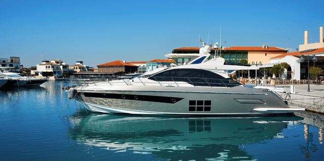 Motor yacht moored in a sunny marina beside waterfront buildings